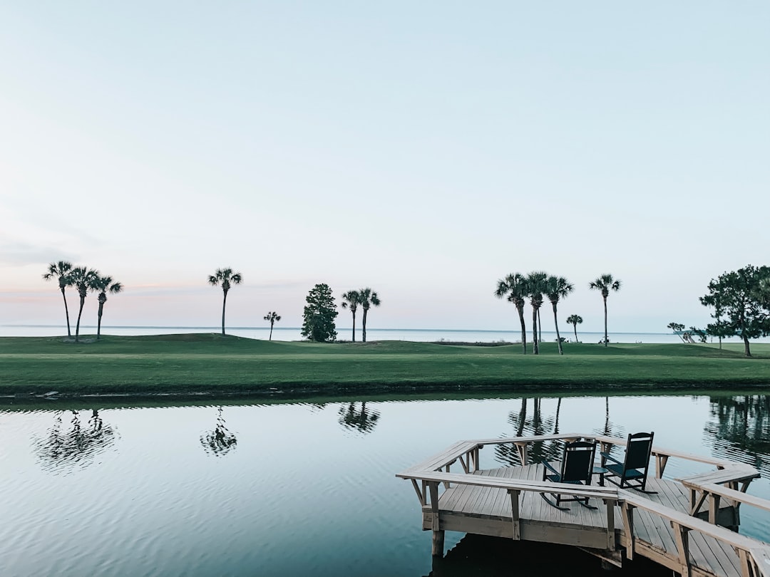 Luxury waterfront estate in South Florida with pool and palm trees at sunset.