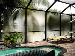 Luxury South Florida home with large impact-rated windows beside a pool.
